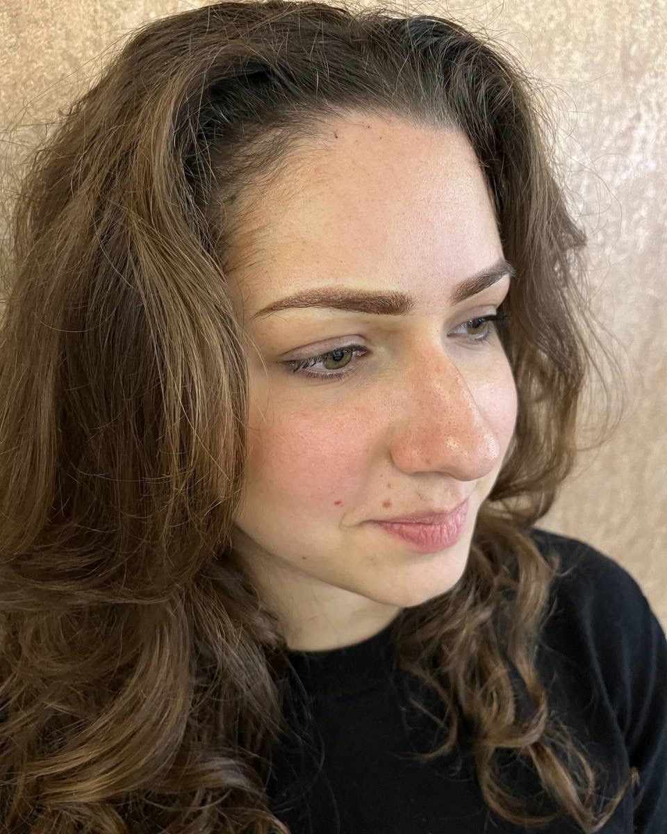 Cliente di tre quarti con le sopracciglia in dermopigmentazione, capelli mossi